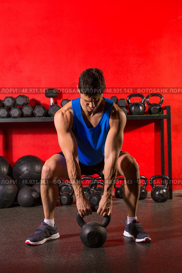 Kettlebell swing workout training man at gym with red walls. Стоковое фото, агентство Ingram Publishing / Фотобанк Лори