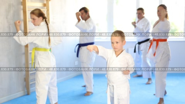 Kid boy and his family repeat movements and learn fighting techniques during martial arts lesson. Стоковое видео, видеограф Яков Филимонов / Фотобанк Лори