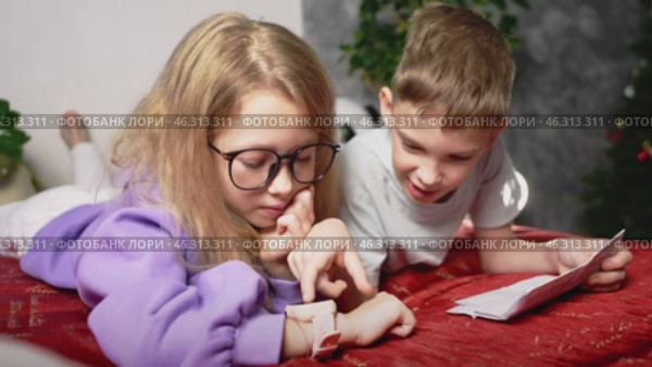 Kids excitedly examine smartwatch, discovering functions together. Boy points to screen while girl navigates menu. Digital curiosity, education, and benefits of smart gadgets in childrens daily life. Стоковое видео, видеограф Енваев Андрей / Фотобанк Лори