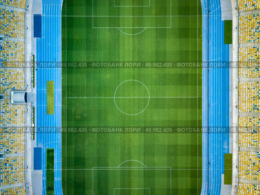KIEV, UKRAINE - July 19, 2018. Birds eye view from drone of the stadium - National Sports Complex Olimpiysky green grass of football field and seats of tribunes before soccer match at summer sunset.. KYIV, UKRAINE - July 19, 2018. NSC Olimpiysky. Aerial view from drone of construction of green football field, tribunes before the game. Top view. Редакционное фото, агентство Ingram Publishing / Фотобанк Лори