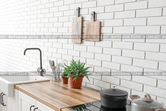 Kitchen counters with sink, houseplants and utensils near white brick wall. Стоковое фото, фотограф Pixel_shot / Фотобанк Лори