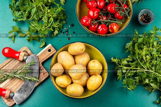 Kitchen table with fresh vegetables, raw potatoes, fresh beautiful tomatoes and bunches of greens. Top view.. Fresh raw potatoes and bunch of wet ripe tomatoes. Стоковое фото, агентство Ingram Publishing / Фотобанк Лори
