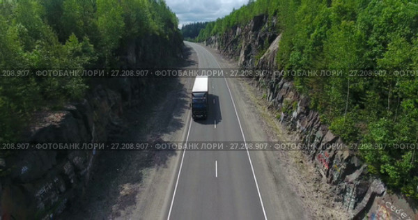 Колонная грузовиков и автомобилей проезжает по дороге, проложенной среди скал (2017 год). Редакционное видео, видеограф Кекяляйнен Андрей / Фотобанк Лори
