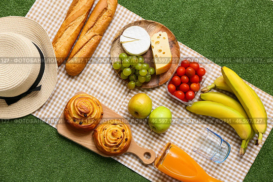 Композиция с вкусной едой для пикника, шляпой и бутылкой сока на фоне зеленой травы. Стоковое фото, фотограф Pixel_shot / Фотобанк Лори
