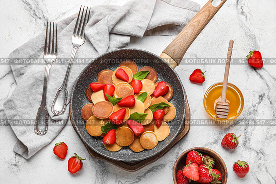 Композиция со сковородкой из вкусных мини-оладьев, клубникой и миской меда на светлом фоне. Стоковое фото, фотограф Pixel_shot / Фотобанк Лори