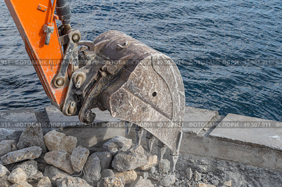 Ковш экскаватора загружает крупные камни. Excavator bucket filled with stones and pieces of concrete. Стоковое фото, фотограф Татьяна Д / Фотобанк Лори