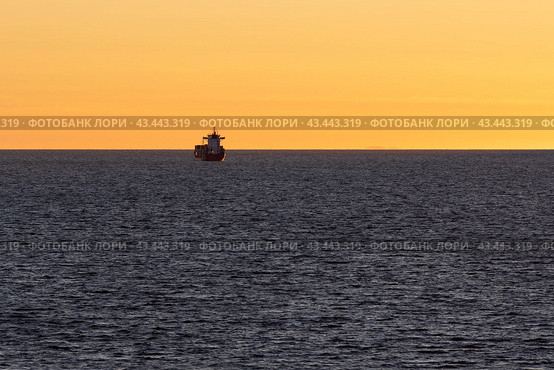 Красивый вечерний морской пейзаж. Вид на грузовое судно в море на закате. Морские контейнерные перевозки. Минималистский пейзаж. Отлично подходит для фона. Стоковое фото, фотограф Андрей Степанов / Фотобанк Лори