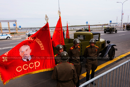 Красное знамя развевается на ветру у мужчин в военной форме времен Великой Отечественной Войны (2022 год). Редакционное фото, фотограф Nikolay Pestov / Фотобанк Лори