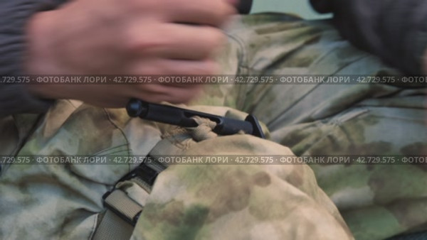 Крупный план руки военного инструктора, поворачивающей патрубок жгута, наложенного на ногу. Обучение на курсах медицинской помощи. Боевой медицинский жгут останавливает кровоток. Стоковое видео, видеограф Воловодов Владимир / Фотобанк Лори