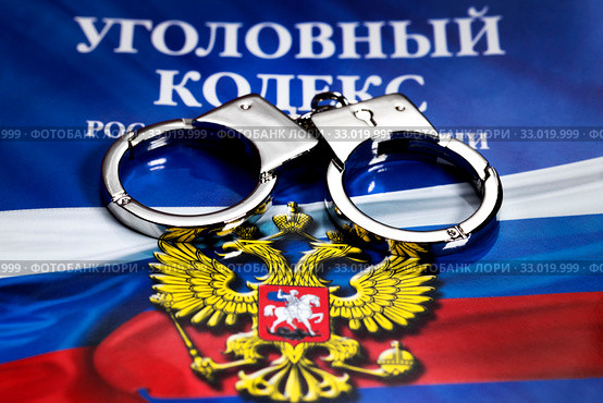 Крупным планом наручники, которые лежат на брошуре с Уголовным кодексом Российской Федерации (2020 год). Редакционное фото, фотограф Николай Винокуров / Фотобанк Лори