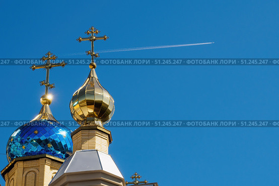 Купола Церкви Пантелеимона Целителя в ессентуках. Domes of the temple with crosses against blue sky and flying plane with white trace. Orthodox church and flying airplane (2019 год). Редакционное фото, фотограф Зарифа Арсланова / Фотобанк Лори