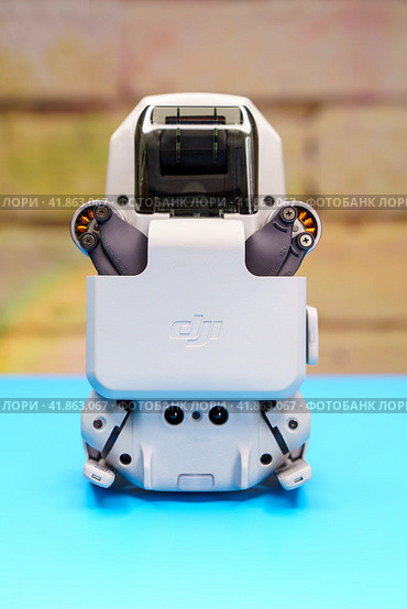Квадрокоптер Dji Mini 2 со сложенными и зафиксированными лапками с моторами на голубом столе во время запрета на полеты дронов (2023 год). Редакционное фото, фотограф Sergei Gorin / Фотобанк Лори