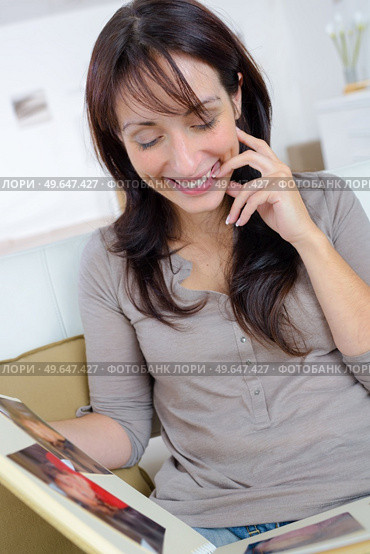 Lady looking through photograph album and smiling. Стоковое фото, агентство Ingram Publishing / Фотобанк Лори