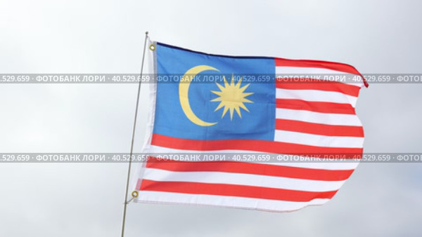 Large flag of Malaysia fixed on metal stick waving against background of cloudy sky during daytime. Стоковое видео, видеограф Яков Филимонов / Фотобанк Лори
