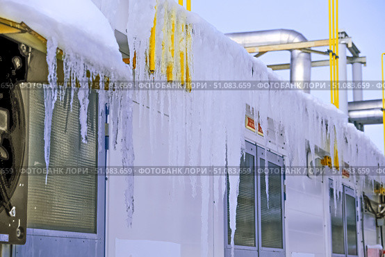 Large ice icicles hang from the roof of the production facility. Security concept. Стоковое фото, фотограф lyudmila Soloveva / Фотобанк Лори