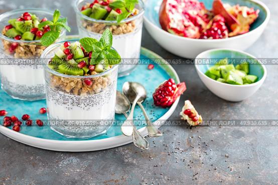 Layered chia pudding parfait with kiwi fruit, pomegranate, granola and yogurt, healthy breakfast. Стоковое фото, агентство Ingram Publishing / Фотобанк Лори