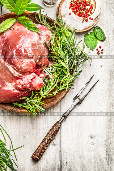 Leg of lamb with meat fork and fresh seasoning on rustic wooden background. Стоковое фото, агентство Ingram Publishing / Фотобанк Лори