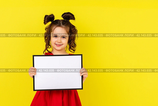 little brunette girl in red drees smiling and holding an empty drawing Board, space for text,isolate on a yellow background. Стоковое фото, фотограф Ирина Михайличенко / Фотобанк Лори