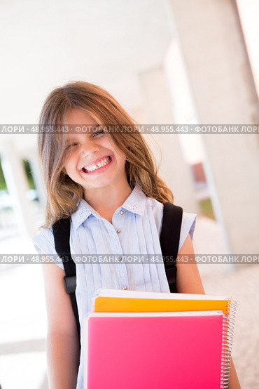 Little cute girl holding books at school. Стоковое фото, агентство Ingram Publishing / Фотобанк Лори