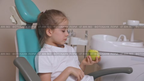 Little girl are eating green apple in the dentist's chair. Healthy teeth concept. Child eat a green apple. Slow motion footage. Стоковое видео, видеограф Ирина Михайличенко / Фотобанк Лори