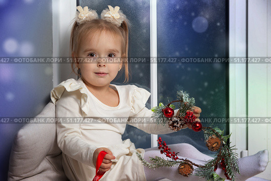 Little happy girl sitting on the windowsill playing with Christmas decor. Стоковое фото, фотограф Лазаренко Светлана / Фотобанк Лори