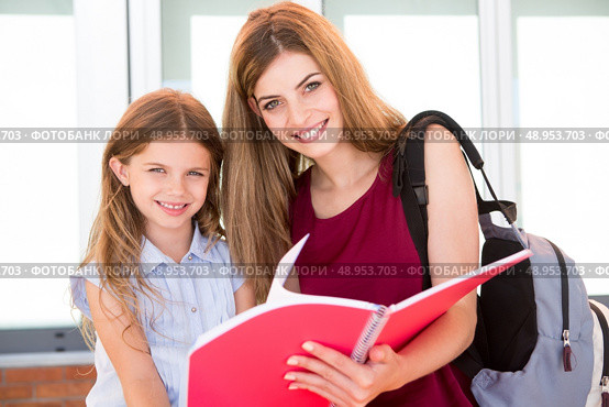 Little school girl showing sketchbook to her mother. Стоковое фото, агентство Ingram Publishing / Фотобанк Лори
