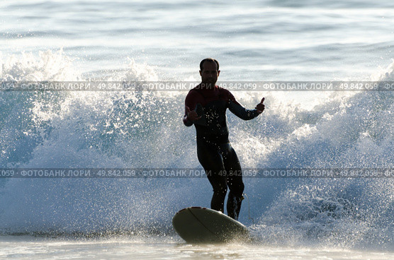 Long boarder surfing the waves at sunset in Portugal. Стоковое фото, агентство Ingram Publishing / Фотобанк Лори