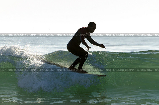 Long boarder surfing the waves at sunset in Portugal. Стоковое фото, агентство Ingram Publishing / Фотобанк Лори