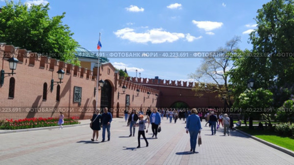 Люди гуляют по Александровскому саду у стен Московского Кремля. Велосипедисты катаются в центре города. Популярный туристический маршрут. Флаг Российской Федерации на флагштоке. Москва, Россия, 30 мая 2022. People walk in the Alexander Garden near the walls of the Moscow Kremlin. Cyclists ride in the city center. A popular tourist route. The flag of the Russian Federation on the flagpole. Moscow, Russia, May 30, 2022. Редакционное видео, видеограф Ирина / Фотобанк Лори