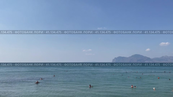 Люди купаются в море. Крым, бухта Провато. Вид на Карадаг. Центральный пляж пгт Орджоникидзе (2023 год). Редакционное видео, видеограф Щеголева Ольга / Фотобанк Лори