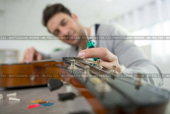 luthier using screwdriver to work on a guitar. Стоковое фото, агентство Ingram Publishing / Фотобанк Лори