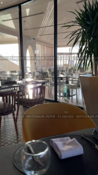 Luxury Arabian resort Empty tables and chairs along white buildings Round tables and chairs at an open-air restaurant An empty cafe, restaurant terrace in an urban environment amid-st lush vegetation greenery. Seating, vintage tables and chairs served for guests. Luxurious reception table Tableware on tablecloths.Interior of restaurant with orange chairs, tables, brick walls. Empty eatery features bar counter, loft design, modern lighting, large windows. Cafe is ready to serve food, beverages for clients. Стоковое видео, видеограф Zita Khasanova / Фотобанк Лори