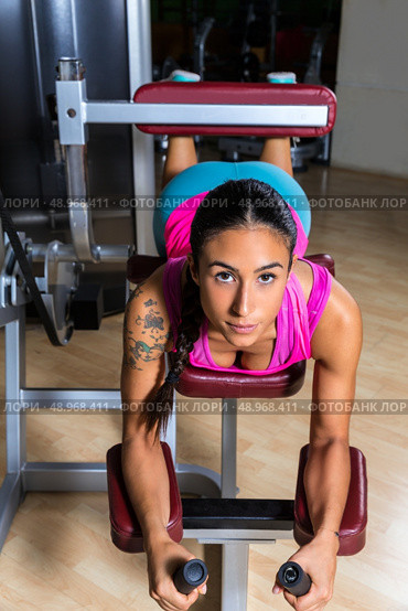 Lying hamstring curl machine girl brunette woman. Стоковое фото, агентство Ingram Publishing / Фотобанк Лори