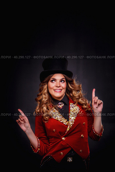 Magician woman looking up presenting show, an illusionist in circus clothes at black background, showing up index fingers. Actress lady in theatre costume. Concept of stage fun perform. Copy ad space. Стоковое фото, фотограф Aleksandr Golubev / Фотобанк Лори