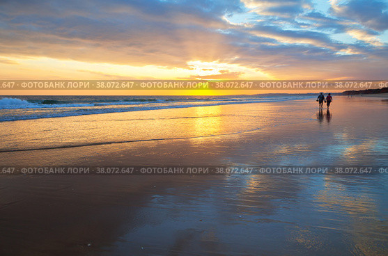 Magnificent southern sunset on the sea. Silhouettes of people walking along the shore of the Atlantic Ocean on a warm evening. Natural summer background. Beautiful seascape. Vilamoura, Falesia, Algarve, Portugal (2012 год). Стоковое фото, фотограф Виктория Катьянова / Фотобанк Лори