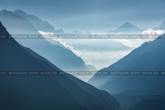 Majestic view of silhouettes of mountains and low clouds at sunset in Nepal. Landscape with high rocks of Himalayan mountains, beautiful blue sky and sun rays. Amazing Himalayas. Nature background . Majestic view of silhouettes of mountains and low clouds at sunset. Стоковое фото, агентство Ingram Publishing / Фотобанк Лори