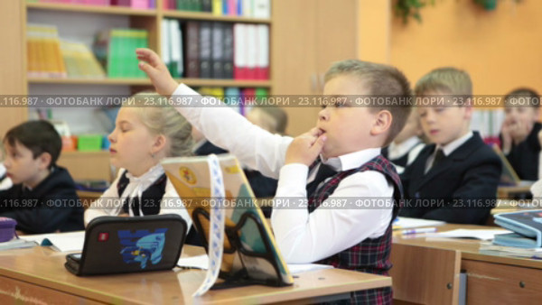 Мальчик ученик первого класса поднимает руку на уроке для ответа (2016 год). Редакционное видео, видеограф Кекяляйнен Андрей / Фотобанк Лори