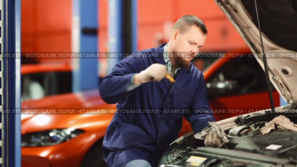 Male auto mechanic checking oil level in car engine in garage. Стоковое видео, видеограф Яков Филимонов / Фотобанк Лори