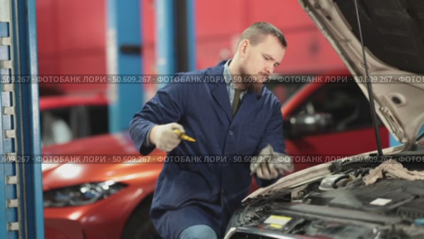 Male auto mechanic checking oil level in car engine in garage. Стоковое видео, видеограф Яков Филимонов / Фотобанк Лори