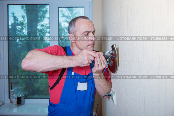 Male electrician connects the lamp on the wall. Стоковое фото, фотограф Наталья Давыдова / Фотобанк Лори