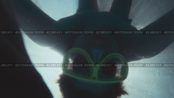 Male figure appearing through streaming sun light underwater to look into camera and rotate. Man having fun diving in swimming pool with mask and taking action camera. Стоковое видео, видеограф Валенти Финаев / Фотобанк Лори