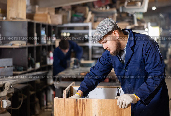 Male furniture assembler assembles wooden table at furniture factory. Стоковое фото, фотограф Яков Филимонов / Фотобанк Лори