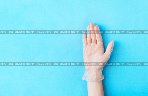 Male hand in transparent vinyl disposable glove raised above blue background. Safety and selfcare concept. Стоковое фото, фотограф Акимова Надежда / Фотобанк Лори