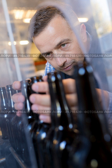 male worker in apron operating bottling equipment on brewery. Стоковое фото, агентство Ingram Publishing / Фотобанк Лори