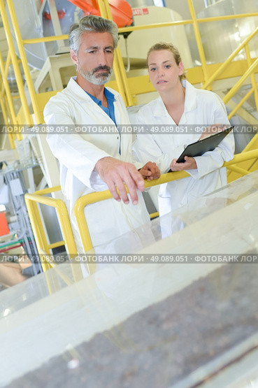 Man and woman in factory watching the production line. Стоковое фото, агентство Ingram Publishing / Фотобанк Лори
