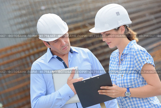 Man and woman in hardhats looking at clipboard. Стоковое фото, агентство Ingram Publishing / Фотобанк Лори