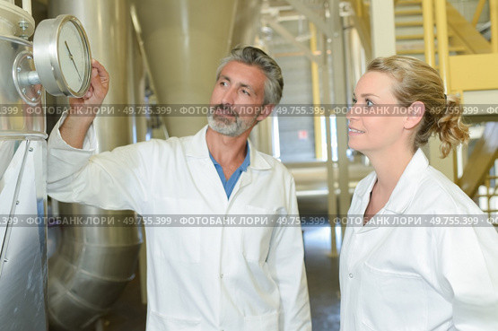 Man and woman looking at gauge on vat. Стоковое фото, агентство Ingram Publishing / Фотобанк Лори