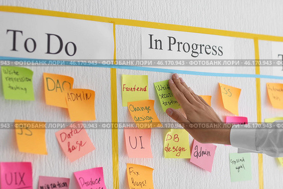 Man attaching sticky note to scrum task board in office. Стоковое фото, фотограф Pixel_shot / Фотобанк Лори