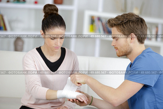 Man bandaging girlfriend's wrist. Стоковое фото, агентство Ingram Publishing / Фотобанк Лори