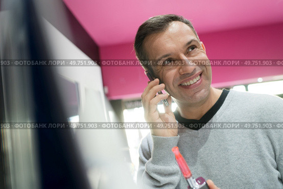 man buying refill vapor cigaretter while on the phone. Стоковое фото, агентство Ingram Publishing / Фотобанк Лори
